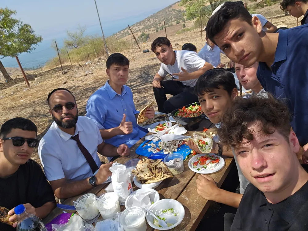 תלמידים ואיש צוות מצטלמים עם ארוחה בשטח - פיתות על המדורה - בוקר כיתה יא בחורשה
