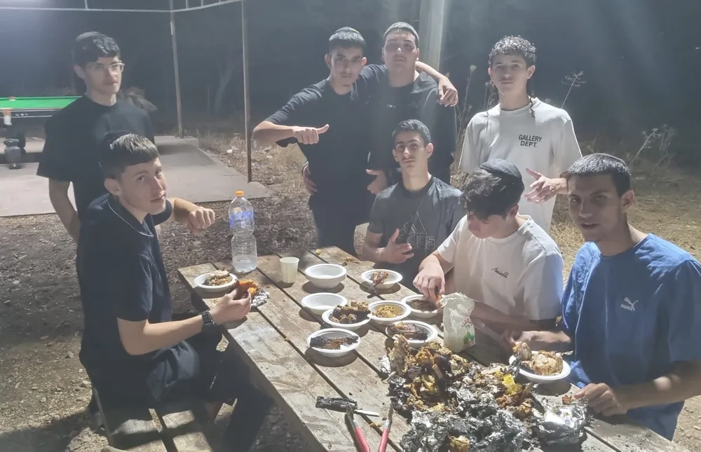 על האש - כיתה יב - קבוצת תלמידים סביב שולחן פיקניק בחוץ - יב יודעים לפנק