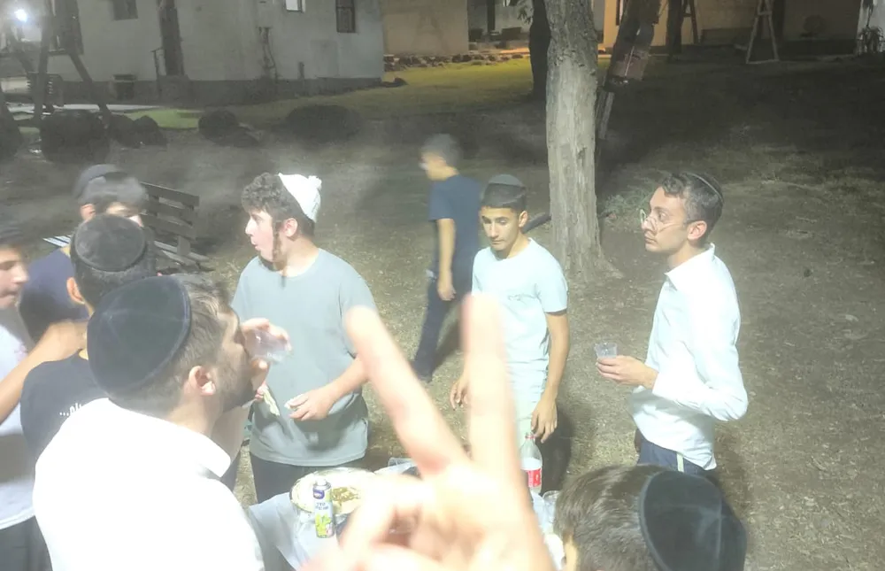 גיבוש כיתות ט ויא - קבוצת תלמידים עומדת סביב שולחן קטן - שתי כיתות, ערב אחד