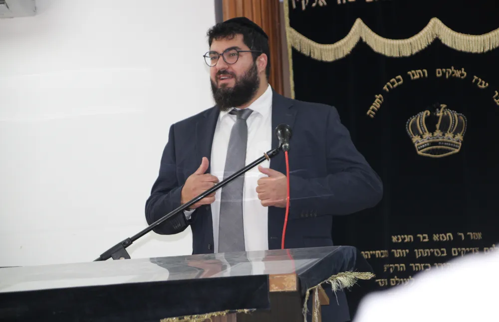 שיחת ראש הישיבה - רב בעל זקן בחליפה עומד מול עמוד שידור עם - שופר, שבת ויום הדין