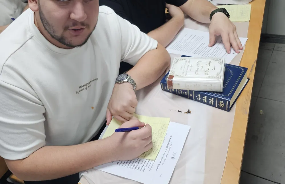 חידון טריוויה - שני בחורים מחייכים לעדשה תוך כדי כתיבה - שלפנו את מה שלמדנו