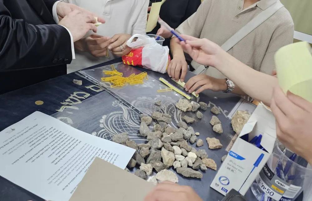 חידון טריוויה - רב וקבוצת תלמידים סביב שולחן עם אבנים - שלפנו את מה שלמדנו