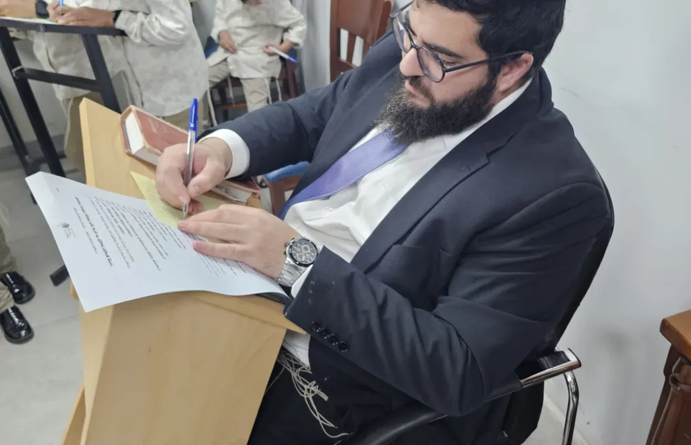 חידון טריוויה - רב בחליפה יושב ליד עמדה וסוקר מסמן דפי - שלפנו את מה שלמדנו