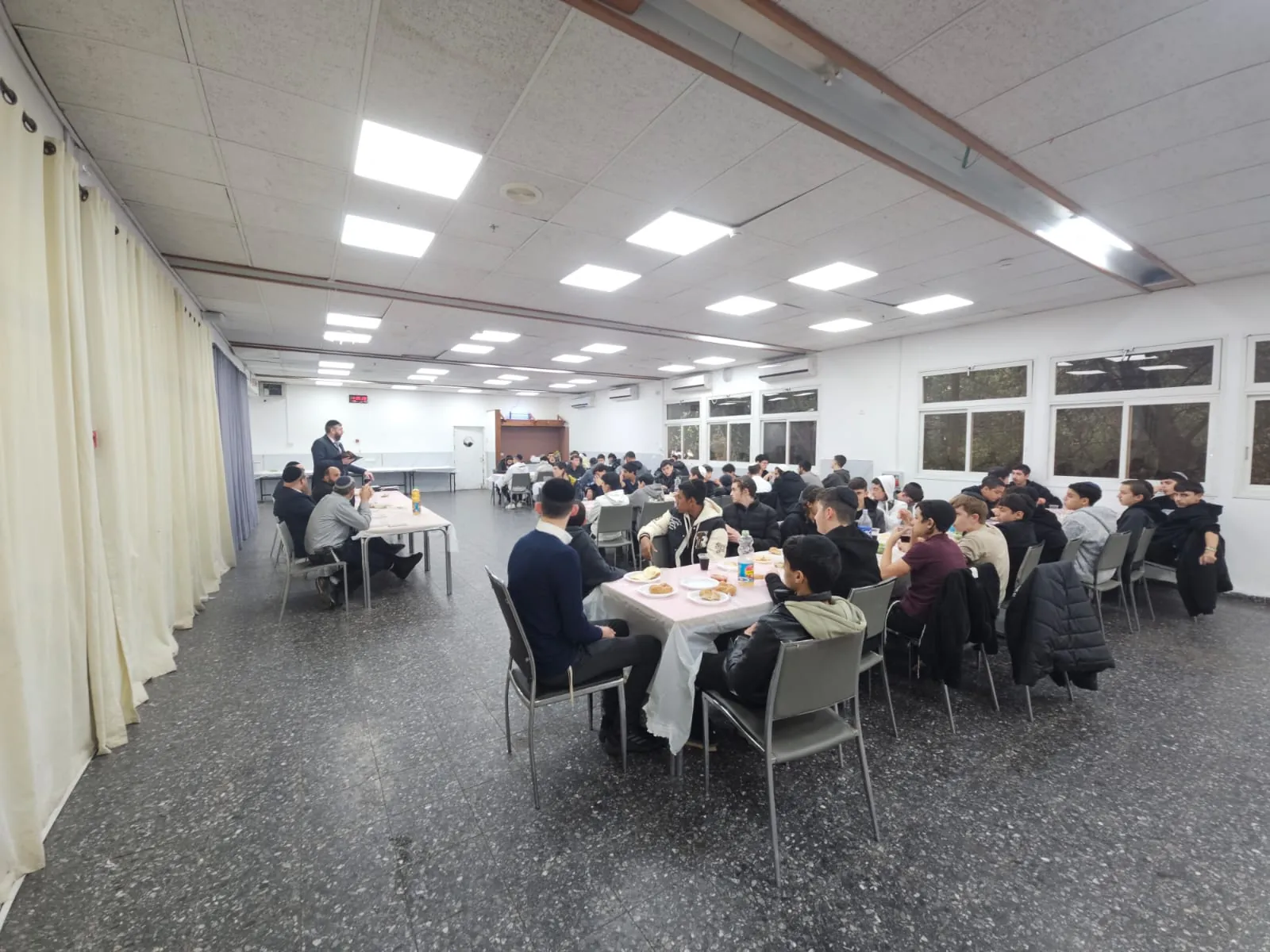 צילום מרוחק של סעודת סיום לתלמידים ואנשי צוות - סיום מסכת - תעודה ביד וסעודה משותפת