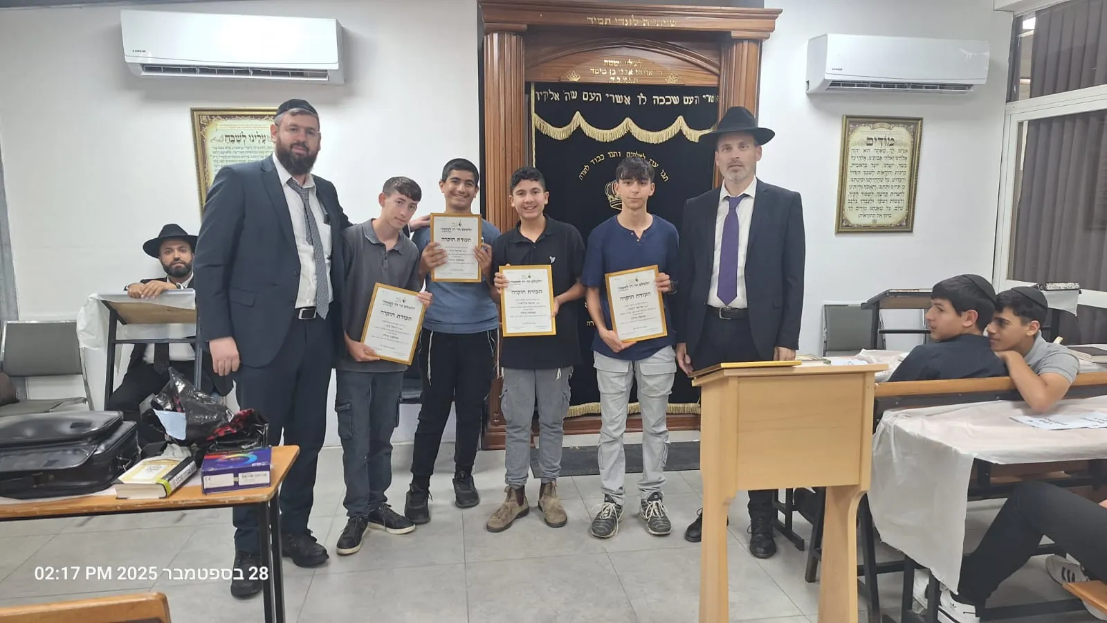 ארבעה תלמידים מציגים תעודות הצטיינות לצד רבנים - ימים נוראים בישיבה, וסיום מסכת שסגר את תשרי
