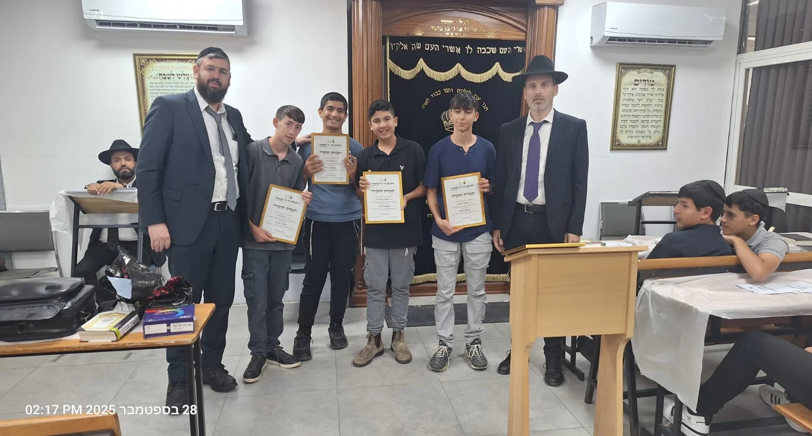 תלמידים עם תעודות הוקרה ליד ההיכל - בין שנה לשנה