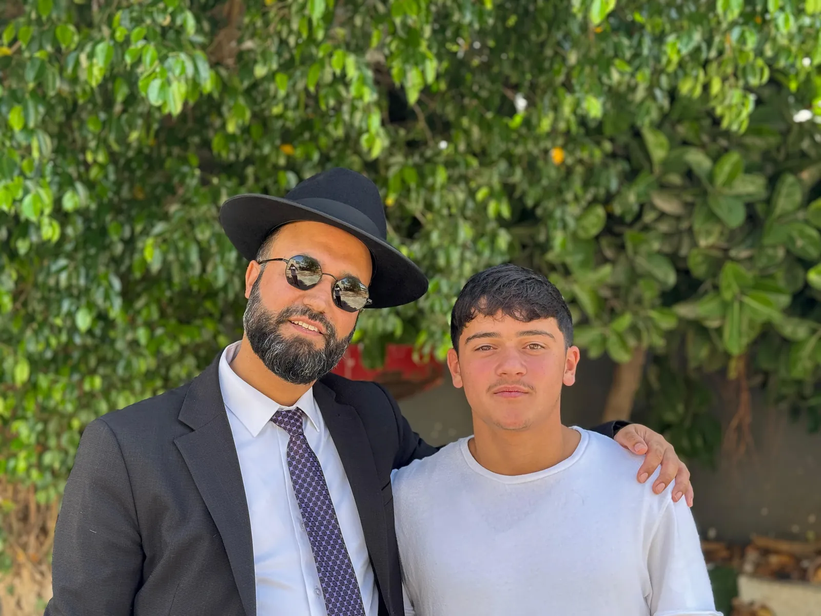 רב ותלמיד מצטלמים יחד מול עצים - ערב ראש השנה בקברי צדיקים