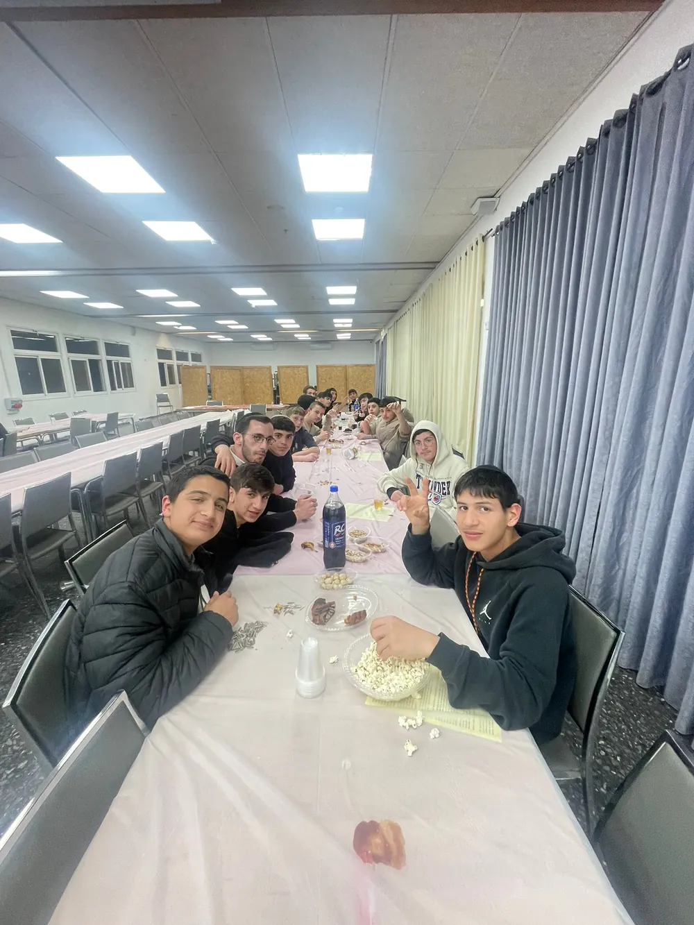 תלמידים ואיש צוות סביב שולחן עם פופקורן וכיבוד - תעודות המחצית, ואחריהן מסיבה