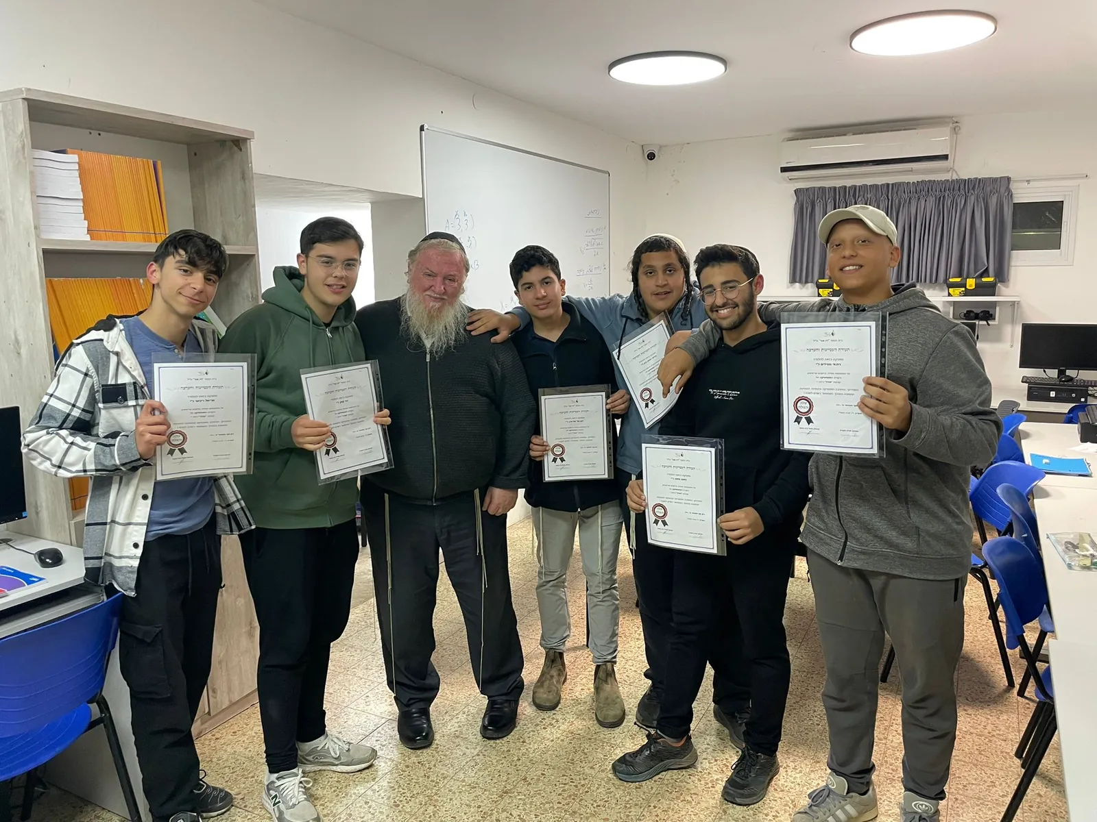 תלמידים מציגים תעודות עם איש צוות בחדר מחשבים - תעודות המחצית, ואחריהן מסיבה