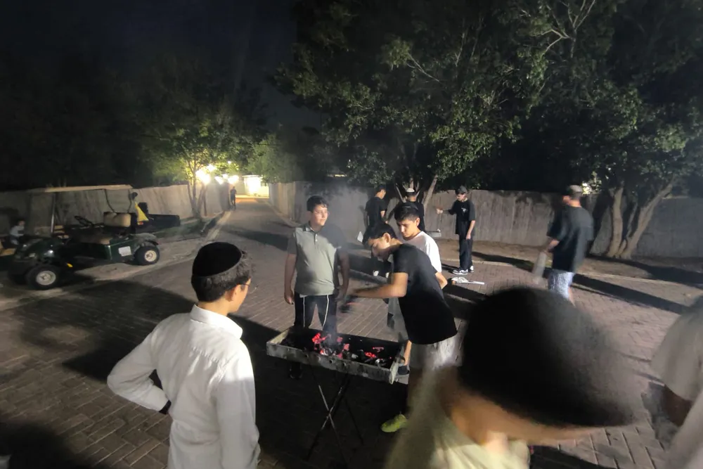 תלמידים סביב מנגל בחצר בלילה - כיתה מול כיתה