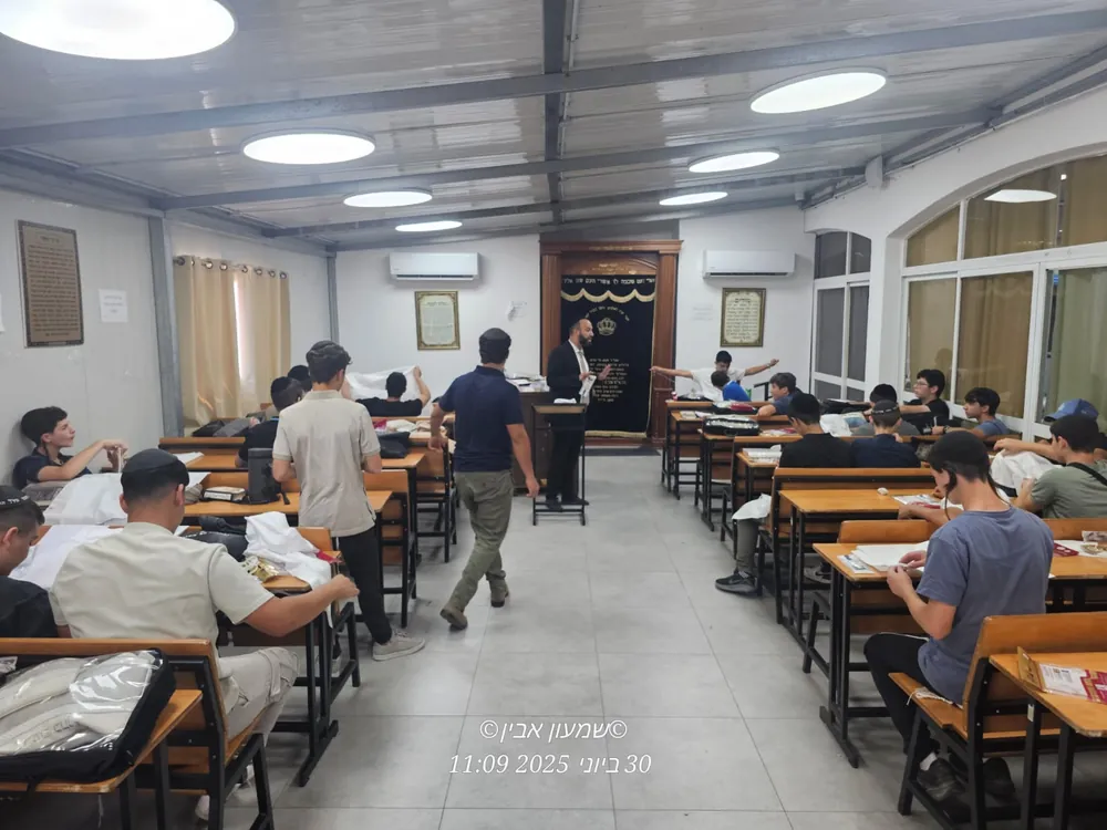 רב מדריך תלמידים סביב שולחנות בסדנת ציציות - סדנת הכנת ציציות בבית המדרש