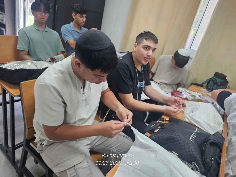 שני תלמידים קושרים ציציות בשולחן - סדנת הכנת ציציות בבית המדרש