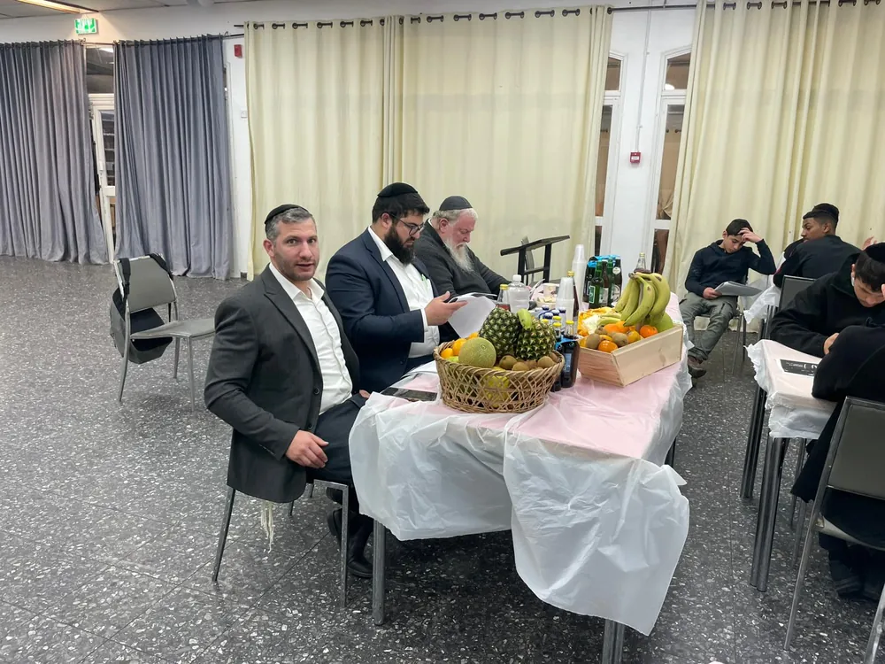 אנשי צוות יושבים ליד סלסלת פירות בסעודת טו בשבט - סעודת ט״ו בשבט