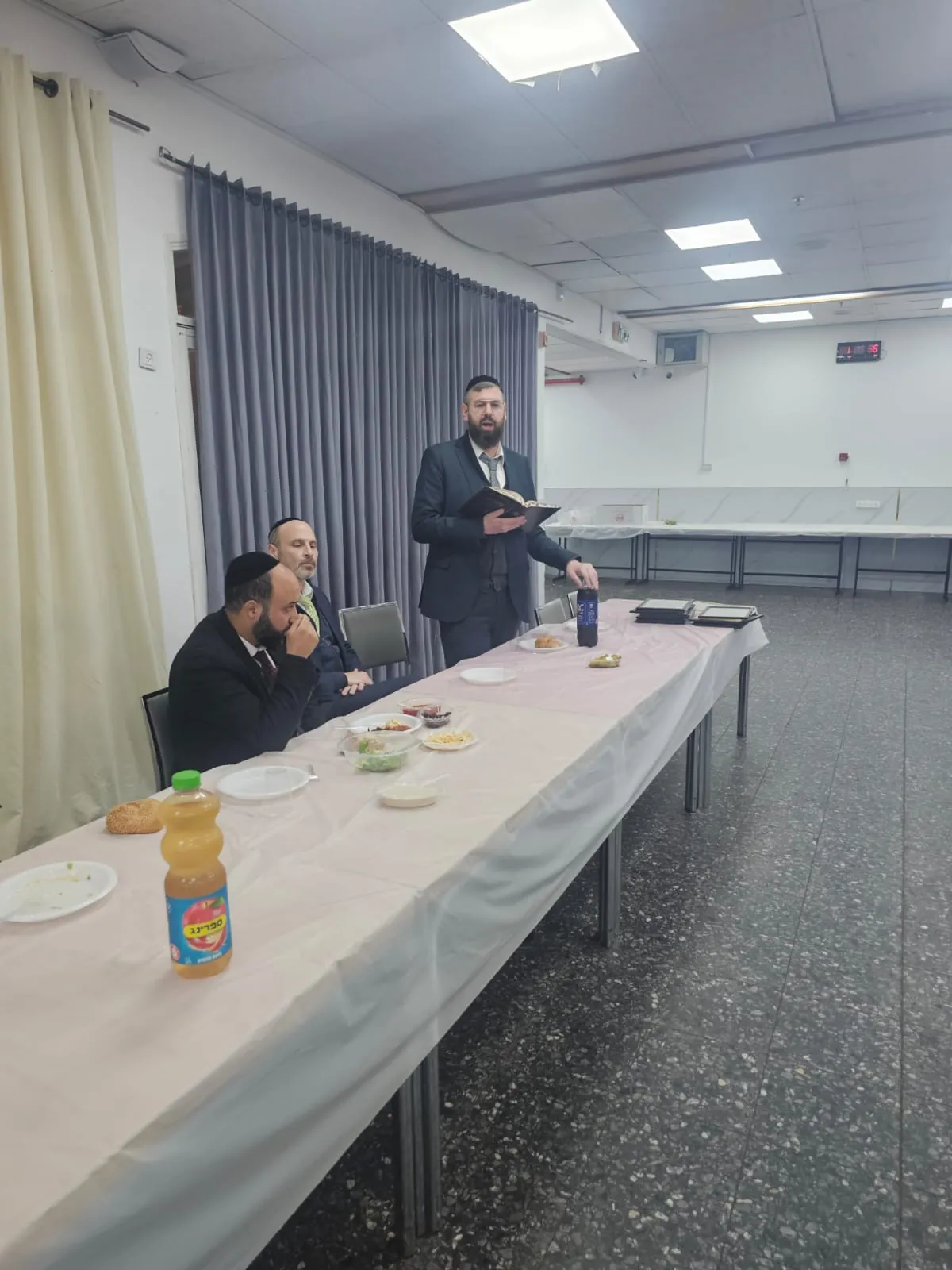 איש צוות קורא מספר ליד שולחן הטקס - סיום מסכת - תעודה ביד וסעודה משותפת