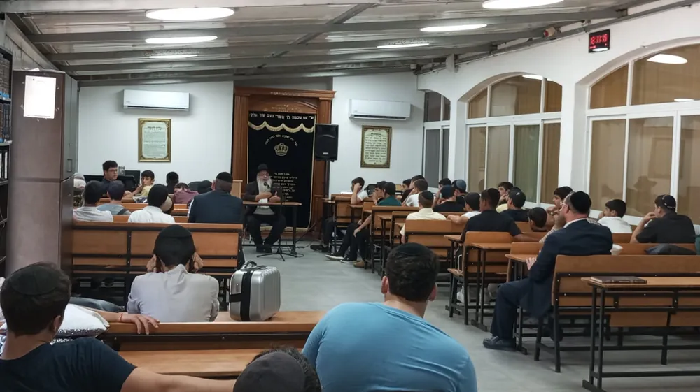תלמידים יושבים בבית המדרש ומאזינים לרב - בית מדרש מלא לקראת הימים הנוראים