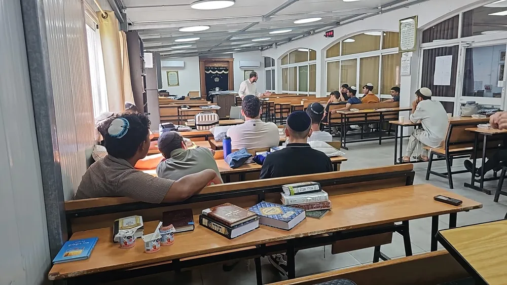 תלמידים מאזינים למרצה בחולצה לבנה בבית המדרש - בית מדרש מלא לקראת הימים הנוראים