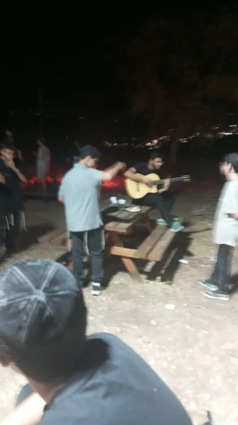 נגינה בגיטרה סביב שולחן פיקניק בלילה - ימים נוראים בישיבה, וסיום מסכת שסגר את תשרי