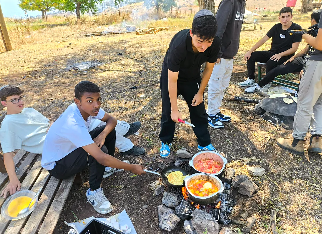 בחורים מבשלים בסירים על האש